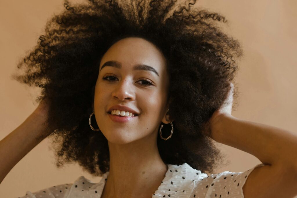 Cheerful woman with curly hair smiling in a studio shot, exuding confidence and joy.
