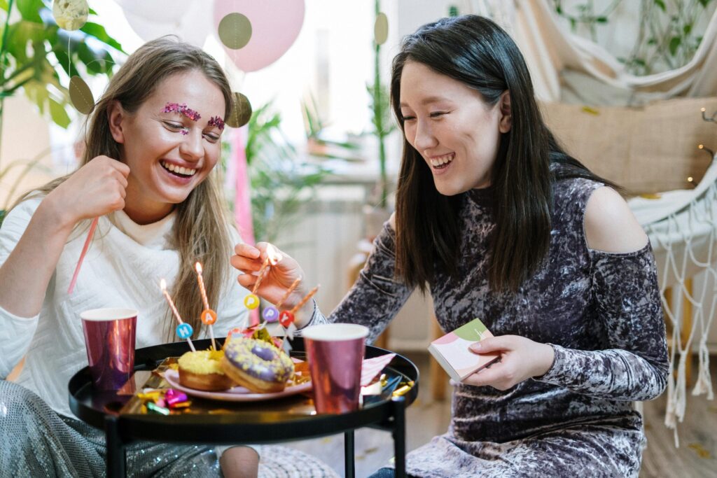 Two women celebrating a birthday indoors with sweets and laughter.